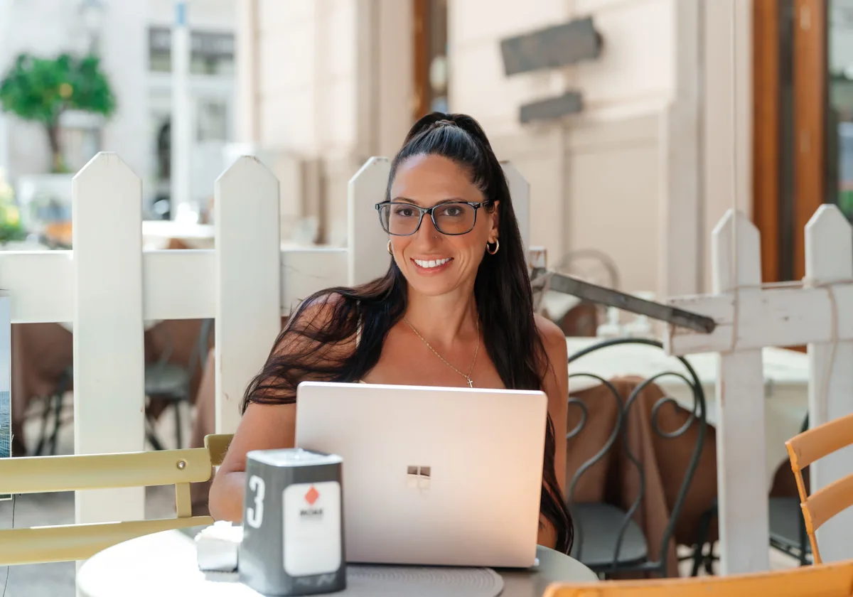 Carla working at her laptop at a cafe table in Castellammare del Golfo
