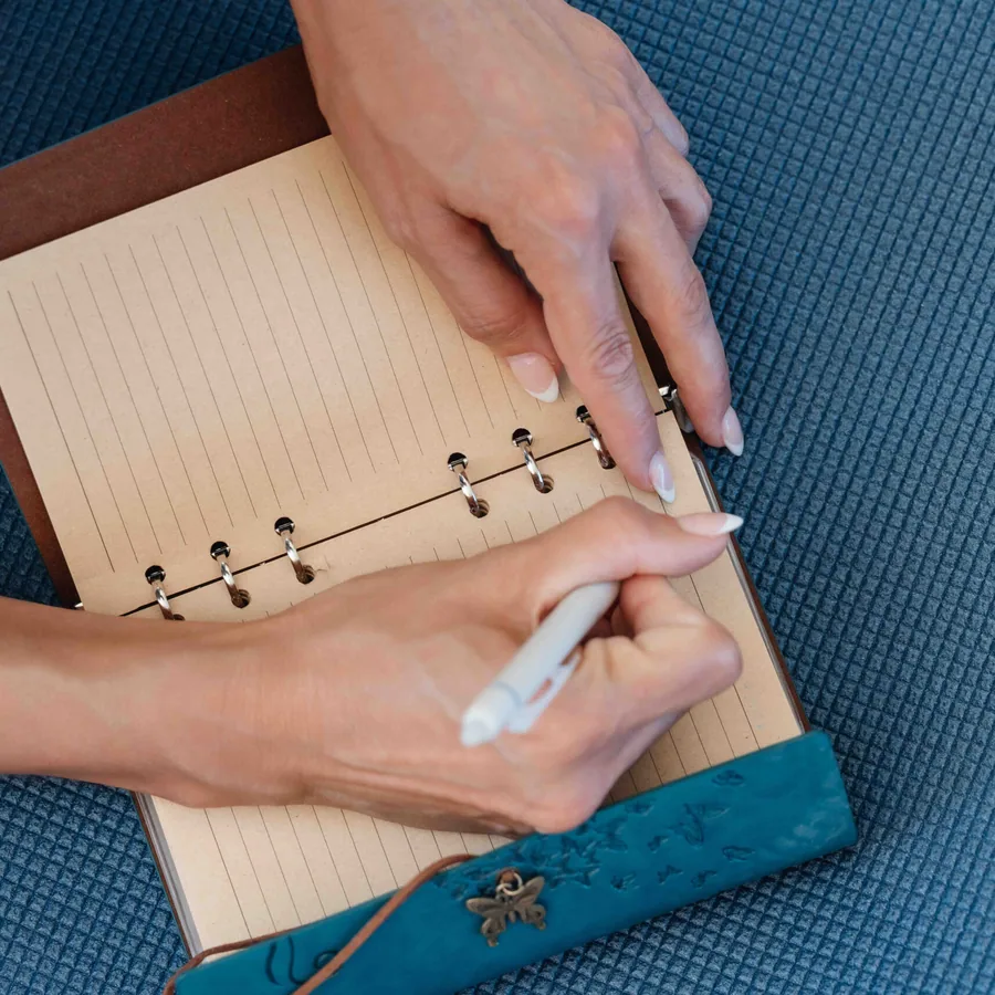 A guest writing in a leather journal on a yoga mat