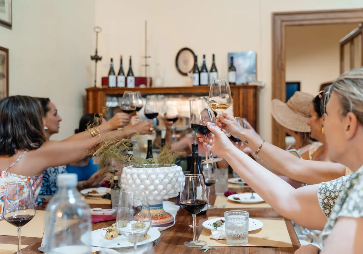 Retreat guests raising glasses around a long table at a Sicilian winery lunch