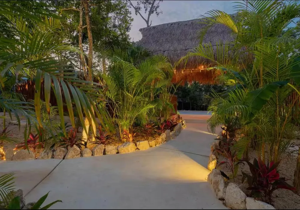 A lantern-lit jungle path between the rooms at night